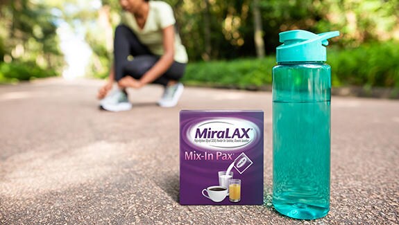 Miralax® next to a water bottle outside with woman getting ready for a run in the background