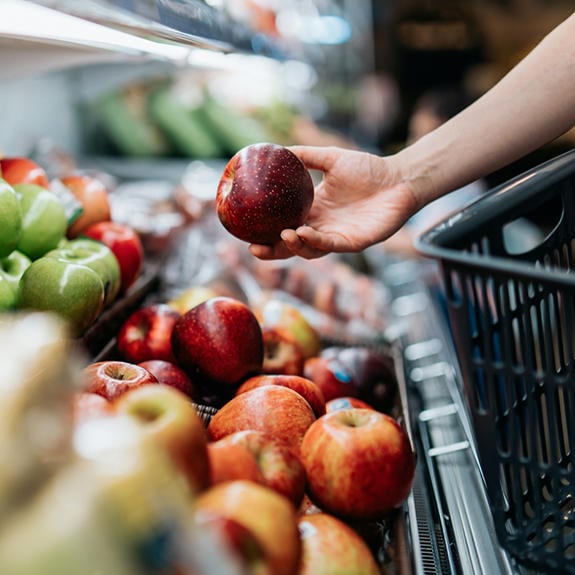 Person selecting apple in grocery store